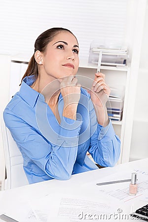 Young woman in blue blouse sitting at desk and dreaming