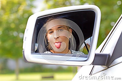 Young woman in a car sticking tongue out