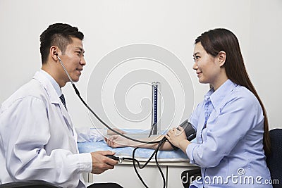 Young Woman Checking Blood Pressure With Male Doctor