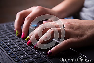 Young woman with colorful nails typing on laptop keyboard