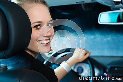 Young woman drives car in wash station