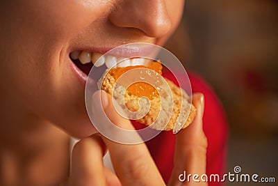 Young woman eating cookie with orange jam