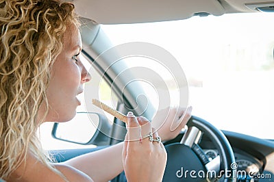 Young woman eating sweets while driving car