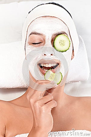 Young woman with face mask and cucumber