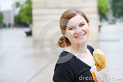 Young woman with fresh baguette on street of a city in France.