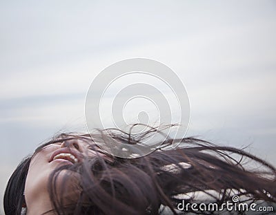 Young woman with hair blowing, looking up