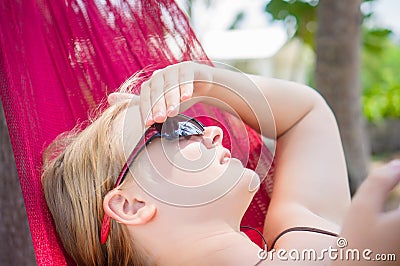 Young woman in hammock under palm trees on ocean beach listen mu