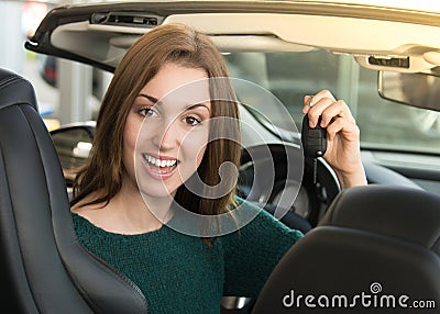 Young woman holding car key inside sports car