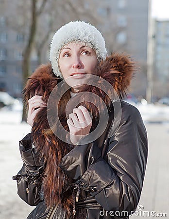 The young woman in a jacket with a fur collar on the street in the winter.Portrait in a sunny day