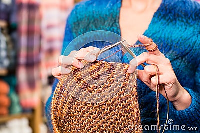 Young woman in knitting shop with circular needle