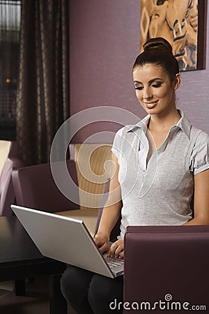 Young woman with laptop at hotel lobby