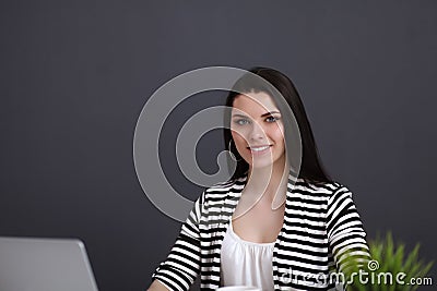 Young woman with a laptop sitting isolated on grey