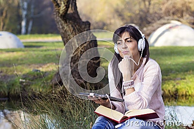 Young woman listening music with her tablet in an autumn park