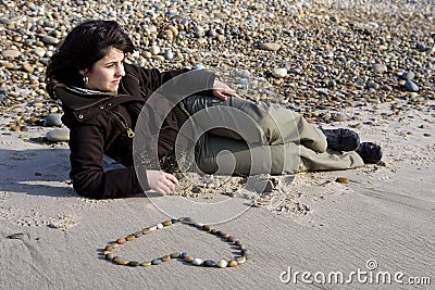 Young woman in love with heart drawn in sand