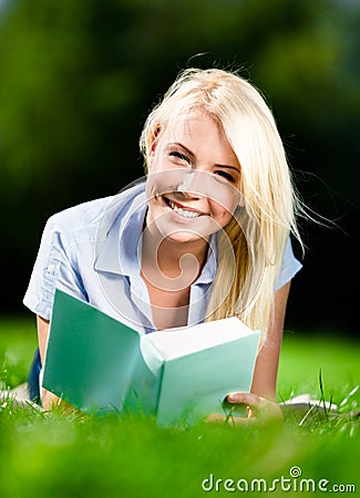Young woman lying on grass with book