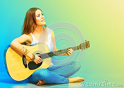 Young woman musician with guitar sitting on a floo