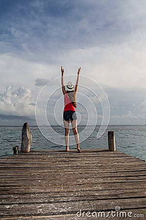 Young woman with open arms enjoying the sunset at the sea