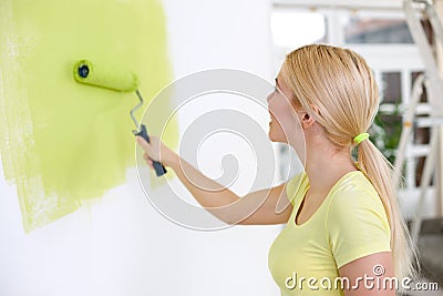 Young woman painting wall