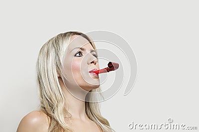 Young woman with party blower looking away over gray background