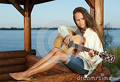 Young woman playing guitar on sunset