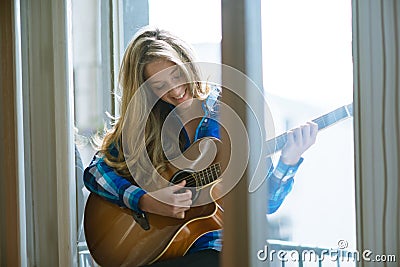 Young woman playing guitar on window
