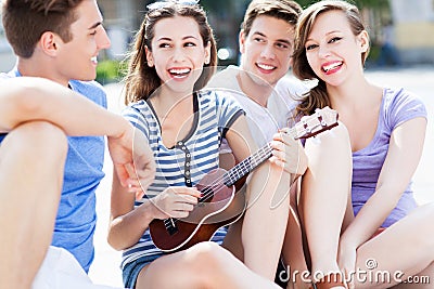 Young woman playing ukulele for friends