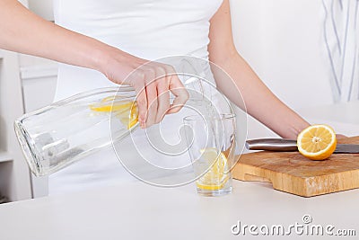 Young woman preparing and drinking lemonade in her kitchen