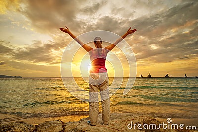 Young woman with raised hands standing on shore and looking to a