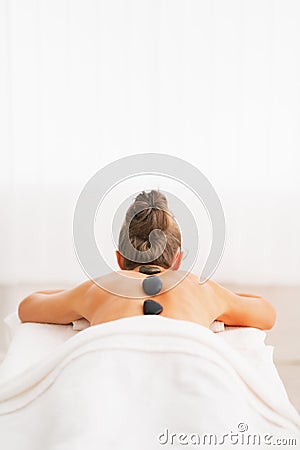 Young woman receiving hot stone massage. rear view