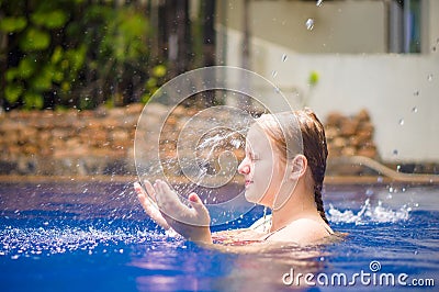 Young woman relax in pool under water shower stream fall to head