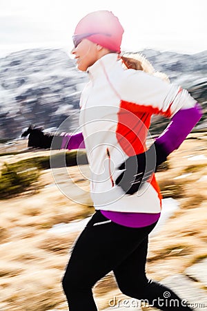 Young woman running in mountains on winter fall