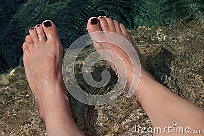 Young woman s manicured feet in water