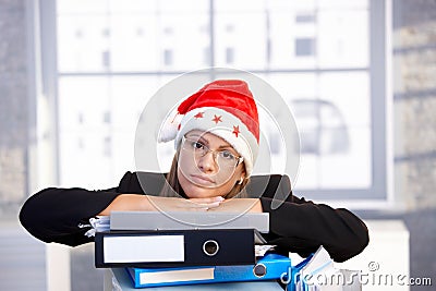 Young woman in santa hat troubled in office