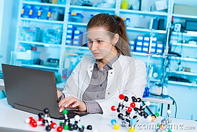 Young woman scientist working at the laboratory. Model of molecule on a