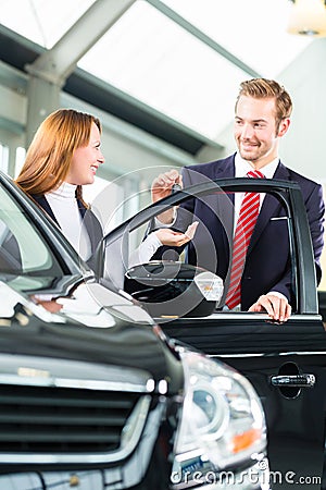 Young woman and seller with auto in car dealership