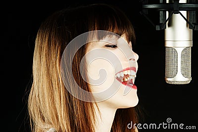 Young woman singing to the microphone in a studio