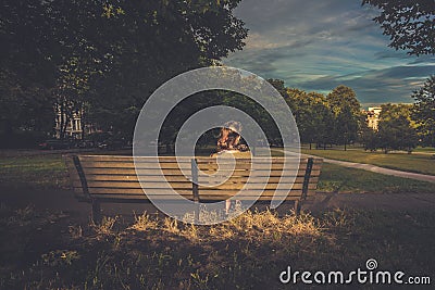 Young woman sitting on a bench at sunset