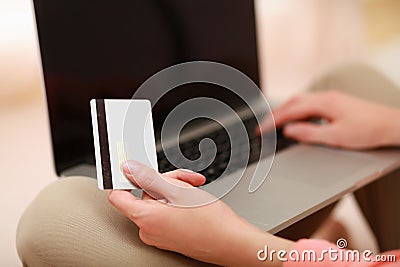Young woman sitting with laptop and holding credit