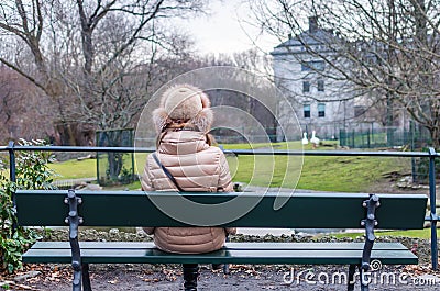 Young woman sitting and thinking on bench in park
