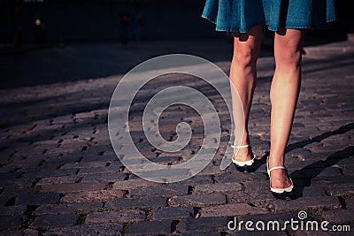 Young woman in skirt walking on a cobbled street