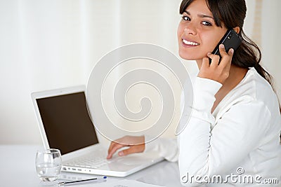 Young woman speaking on cellphone looking at you