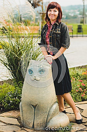 Young woman standing near funny cat statue