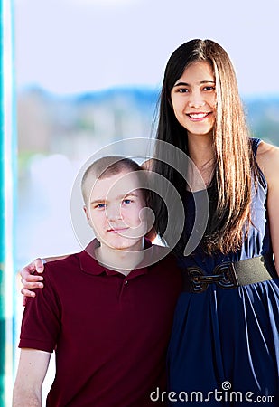 Young woman standing next to seated young man by a lake