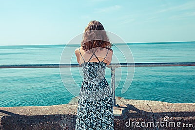 Young woman standing on a pier by the ocean