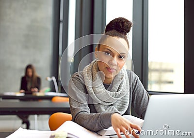 Young woman studying in library using laptop