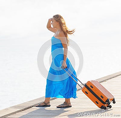 Young woman with suitcase on the pier