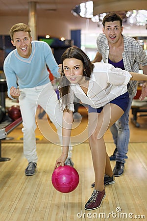 Young woman throws ball in bowling
