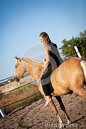 Young woman training horse outside in summer