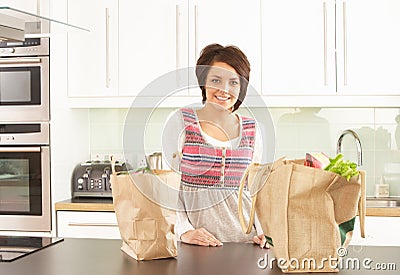 Young Woman Unpacking Shopping In Modern Kitchen