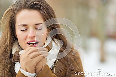 Young woman warming hands in winter outdoors